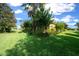 Beautiful lawn featuring lush, green grass and mature trees under a partly cloudy, bright blue sky at 9948 Sw 69Th Ln, Ocala, FL 34481