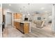 Open kitchen with stainless appliances, island with sink, wood cabinets, and views into the living area at 10597 Sw 90Th Street Rd, Ocala, FL 34481