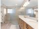 Bright main bathroom featuring a double vanity, walk-in shower with glass panel, and tile surround at 10597 Sw 90Th Street Rd, Ocala, FL 34481