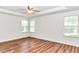 Spacious bedroom with wood flooring, three windows, and a ceiling fan at 10819 Sw 84Th Ter, Ocala, FL 34481