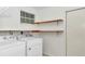 Well-lit laundry room features a washer, dryer, and shelf for storage at 10819 Sw 84Th Ter, Ocala, FL 34481