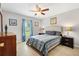 Well-lit bedroom features a ceiling fan, soft blue curtains, and wood-look flooring at 12178 Se 174Th Pl, Summerfield, FL 34491