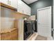 Well-equipped laundry room features modern washer and dryer with white cabinetry and decorative accents at 155 Marion Oaks Pass, Ocala, FL 34473