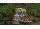 An aerial view showcases a home with gray roof amidst a wooded landscape and paved driveway at 158 Guava Pass, Ocklawaha, FL 32179