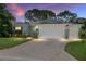 Charming single-story home with a well-manicured lawn and a three-car garage with lights on at 16023 Sw 14Th Avenue Rd, Ocala, FL 34473