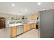 Well-lit kitchen with stainless steel appliances, light wood cabinets and an island with a countertop and attached dining area at 16023 Sw 14Th Avenue Rd, Ocala, FL 34473