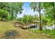 Scenic dock with steps and a covered area overlooking the calm river, surrounded by greenery at 19620 Fox Trl, Dunnellon, FL 34432