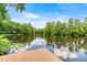 Wooden dock overlooking the calm lake, surrounded by lush trees and clear sky at 19620 Fox Trl, Dunnellon, FL 34432