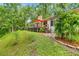 Home's rear exterior with deck, patio seating, a stone chimney, and lush landscaping at 19620 Fox Trl, Dunnellon, FL 34432