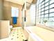Bathroom featuring a garden tub and shower with sliding glass doors, and a glass block window and white cabinets and trim at 2100 Nw 50Th Cir, Ocala, FL 34482