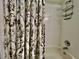 Close up of tiled shower and bathtub with decorative shower curtain and handy shelving unit at 2100 Nw 50Th Cir, Ocala, FL 34482