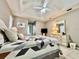 This is a nice bedroom featuring a ceiling fan, tray ceiling, tile floors, and a large bed with a beautiful quilt at 2100 Nw 50Th Cir, Ocala, FL 34482