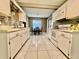 Galley kitchen with white appliances, tiled floor, and an adjacent dining space with a table at 2100 Nw 50Th Cir, Ocala, FL 34482