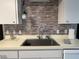 Close-up of the stainless steel kitchen sink with brick-like backsplash and neutral-toned cabinets at 2100 Nw 50Th Cir, Ocala, FL 34482