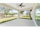 Inviting covered porch with ceiling fan opens to a spacious grassy backyard with shade trees and a clear view at 26 Water Track Dr, Ocala, FL 34472