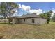 Spacious backyard featuring a covered patio offers ample green space and beautiful landscaping for outdoor activities and relaxation at 26 Water Track Dr, Ocala, FL 34472