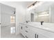 Bright bathroom featuring double vanity, large mirror, black fixtures, and an open doorway leading into a bedroom at 26 Water Track Dr, Ocala, FL 34472