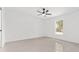 A bedroom with neutral colored walls, a ceiling fan, and a window for natural light at 26 Water Track Dr, Ocala, FL 34472