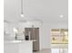 Bright kitchen with stainless steel refrigerator, white cabinets, and view of a back yard through sliding glass doors at 26 Water Track Dr, Ocala, FL 34472