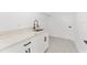 Well-appointed laundry room features a modern sink, elegant quartz countertop, and ample storage in white cabinets, next to a door at 26 Water Track Dr, Ocala, FL 34472