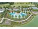 Aerial view of a resort-style pool with palm trees, sun loungers, and a scenic lake backdrop at 4474 Nw 53Rd Ave Rd, Ocala, FL 34480