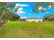 Beautiful backyard view showcasing the manicured lawn, screened patio, and colorful trees under a blue sky with fluffy clouds at 6172 Sw 101St Pl, Ocala, FL 34476