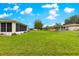 Wide shot of the backyard showcasing the green grass, screen enclosure, trees, and a secure fence, ideal for Gathering enjoyment at 6172 Sw 101St Pl, Ocala, FL 34476