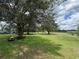 Lush backyard with mature trees and a riding lawn mower for easy maintenance at 6773 Se 87Th St, Ocala, FL 34472