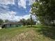 View of a single-story home with a stone facade, a propane tank and a lush green backyard at 6773 Se 87Th St, Ocala, FL 34472
