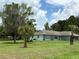 Charming single-story home with light green paint and stone accents sits on a lush green lawn with mature trees at 6773 Se 87Th St, Ocala, FL 34472