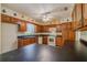Classic kitchen with wood cabinetry, black countertops, and white appliances at 6773 Se 87Th St, Ocala, FL 34472