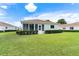 Back exterior view of home showing screened in porch and lush green lawn at 8689 Se 141St Street Rd, Summerfield, FL 34491