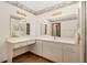 Bathroom with double mirrors, white vanity with drawers and cabinets, and wood grain flooring at 8959 Sw 96Th Ln # A, Ocala, FL 34481