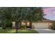 Inviting home exterior with a well-maintained lawn, mature shade tree, and warm, inviting lighting at 9222 Sw 97Th Cir, Ocala, FL 34481