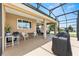 A screened-in patio with seating, a grill and a view of the well-maintained lawn at 9222 Sw 97Th Cir, Ocala, FL 34481