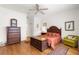 Cozy bedroom features wood floors, a ceiling fan, and a decorative trunk at the foot of the bed at 9746 Sw 89Th Loop, Ocala, FL 34481