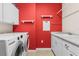 Laundry room featuring a washer and dryer with a red accent wall and white cabinets at 9926 Sw 95Th Loop, Ocala, FL 34481