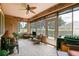 Bright sunroom with multiple seating areas, a ceiling fan, and views of the lush surroundings at 13170 Se 92Nd Court Rd, Summerfield, FL 34491