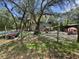 View of the backyard enclosed by chain link fencing, featuring play equipment and an abundance of tree coverage at 15536 Se 203Rd Ave, Umatilla, FL 32784