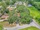 An aerial shot shows a home with a red roof, nestled among mature trees and landscaping in a quiet neighborhood at 2676 Se 52Nd Ave, Ocala, FL 34480