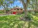 Home with a red roof, beautiful front lawn, and mature shade trees in a residential setting at 2676 Se 52Nd Ave, Ocala, FL 34480