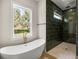 Bright bathroom with free-standing tub, walk-in shower with green tile, and a large window providing natural light at 2792 Se 29Th St, Ocala, FL 34471
