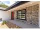 Inviting front porch featuring textured stone walls, a decorative rock garden, and a vibrant red front door at 28 Water Track Dr, Ocala, FL 34472