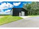 Black steel building with a white door, set on a well-maintained lawn, suitable for a workshop or storage at 3440 Sw 66Th St, Ocala, FL 34476