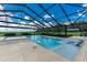 Wide angle of a screened-in pool featuring a jacuzzi and sun shelf with built-in loungers at 3440 Sw 66Th St, Ocala, FL 34476