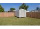 Backyard featuring a storage shed on a lush green lawn enclosed by a wooden fence under a clear blue sky at 3645 Sw 151St Ct, Ocala, FL 34481