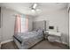 Cozy bedroom with a tufted headboard, grey bedding, modern vanity, and natural light streaming through the pink curtains at 3645 Sw 151St Ct, Ocala, FL 34481