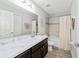 Clean bathroom offers a shower-tub combo, marble countertop and dark wood cabinets at 4955 Se 89Th Place Rd, Ocala, FL 34480