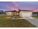 Beautiful home at sunset with a large white garage door and nicely paved driveway at 5 Dogwood Loop Ave, Ocala, FL 34472