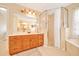 Bright bathroom with wooden vanity, neutral countertop, framed mirror, a glassed shower, and a soaking tub at 5459 Sw 86Th St, Ocala, FL 34476